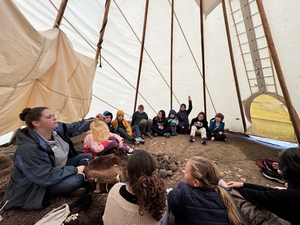 educator shows a bladder to students sitting in tipi