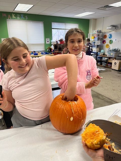 student pulls seeds from inside pumpkin