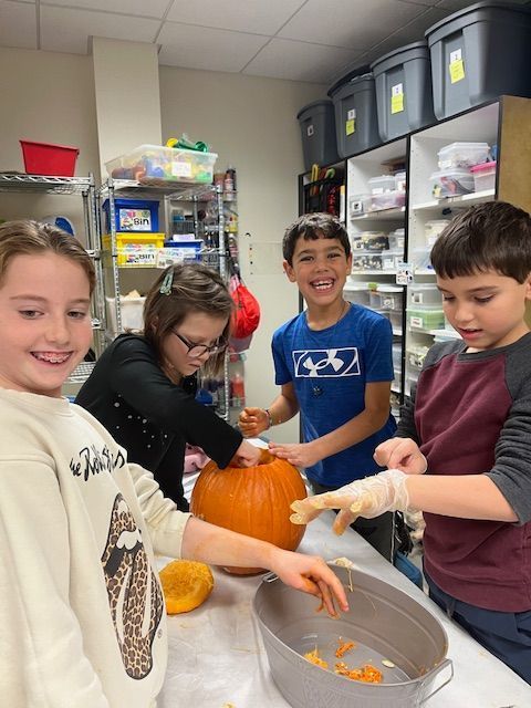 students take seeds from pumpkin and place them in a bucket