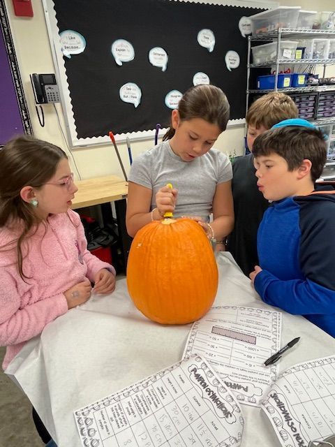 student carves open pumpkin