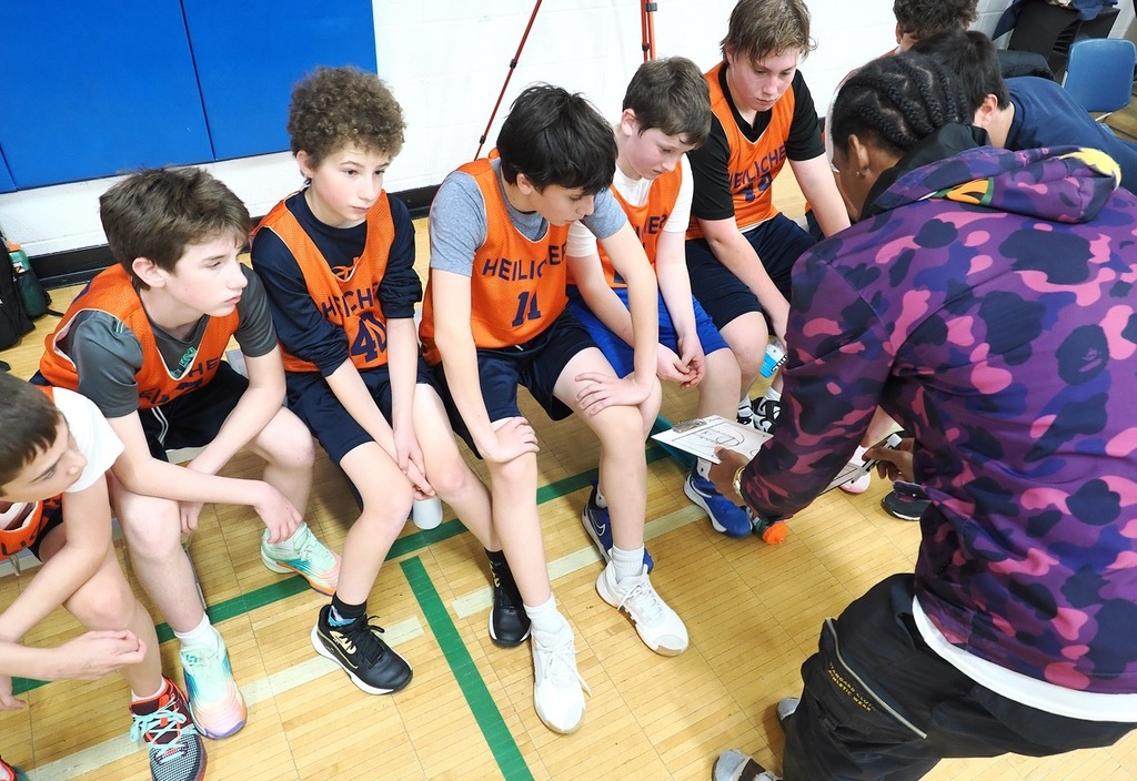 basketball coach goes over play with players on bench