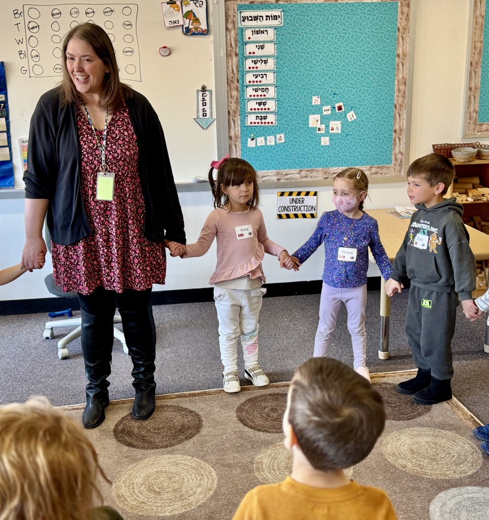 kindergarten teacher and pre-k students hold hands in circle