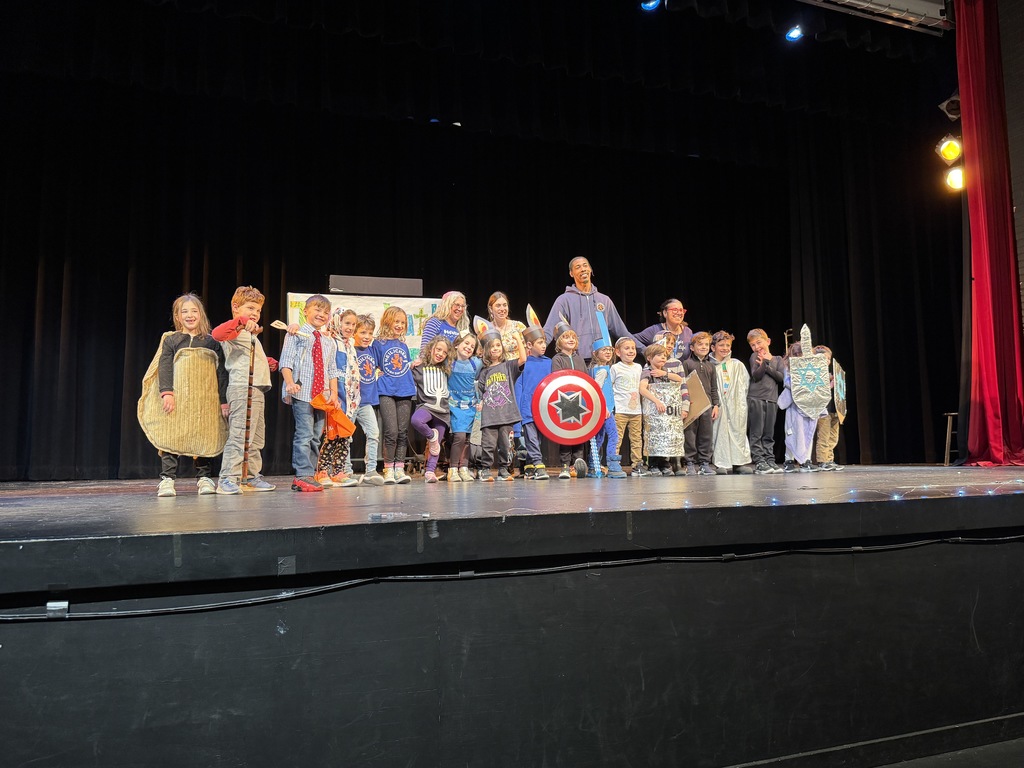 first grade class poses on stage