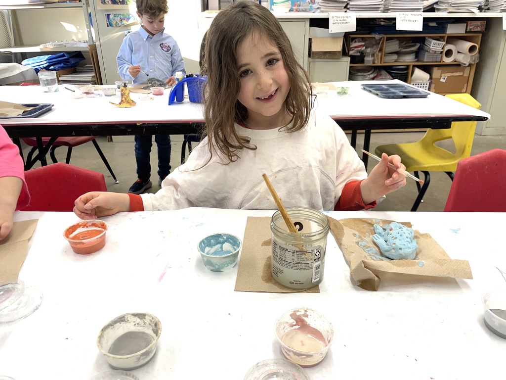 student glazes clay animals