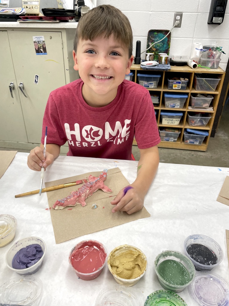 student glazes clay animals