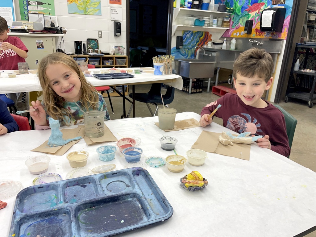 two students glaze clay animals