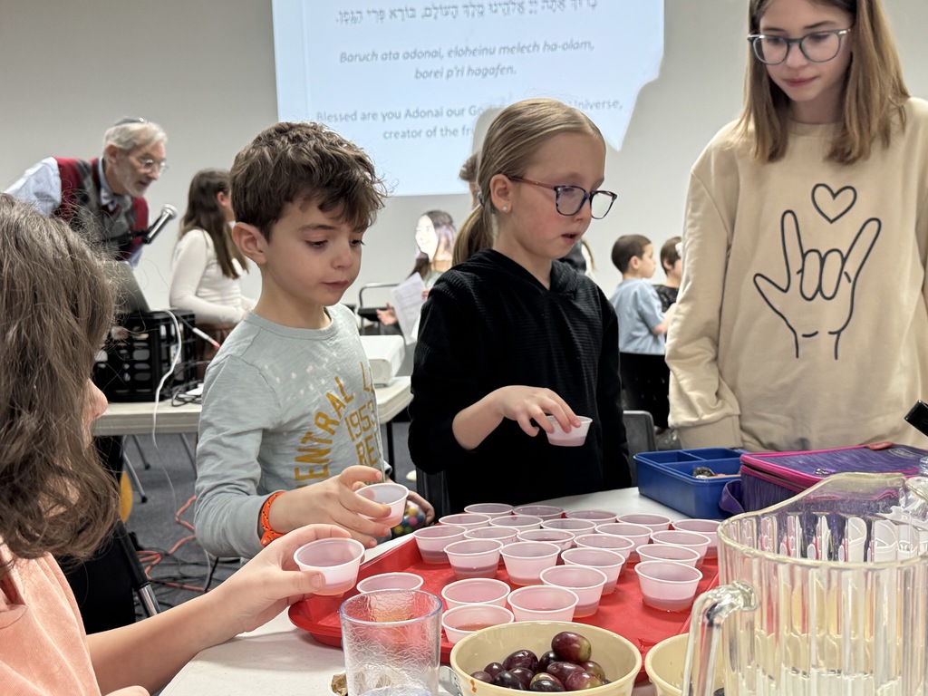 students pick up cups of grape juice before reciting blessing