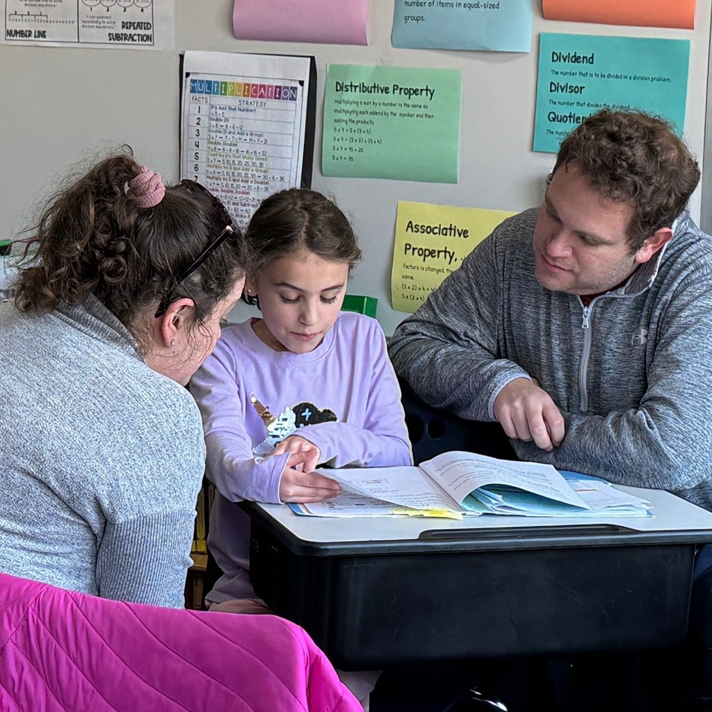 student shows workbook to guests