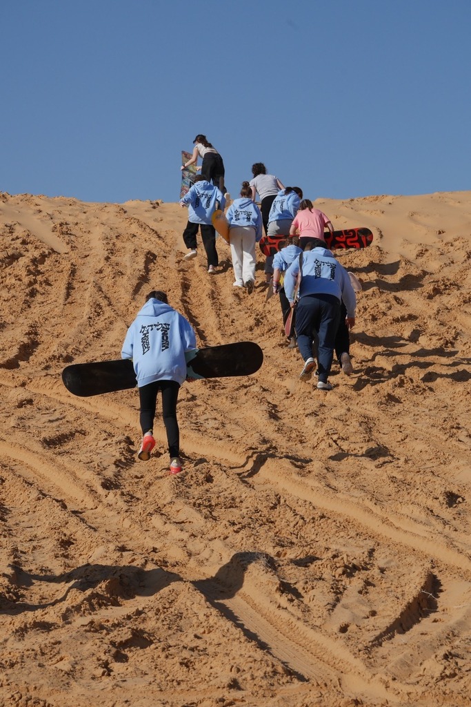 students climb sand dune