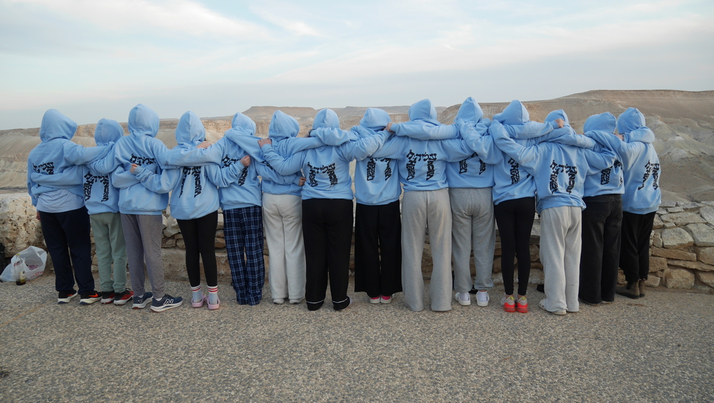 Aliyah Chet students in matching sweatshirts look over desert with arms around each other