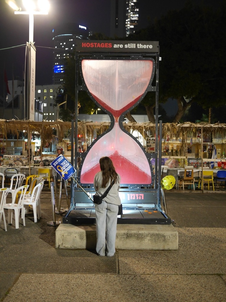 student stands in front of hour glass sign that says Hostages are still there