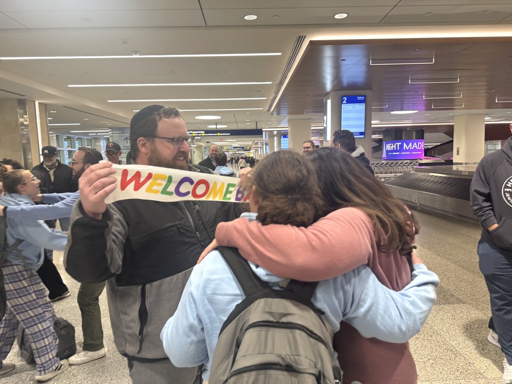 dad holds welcome sign as mom hugs daughter