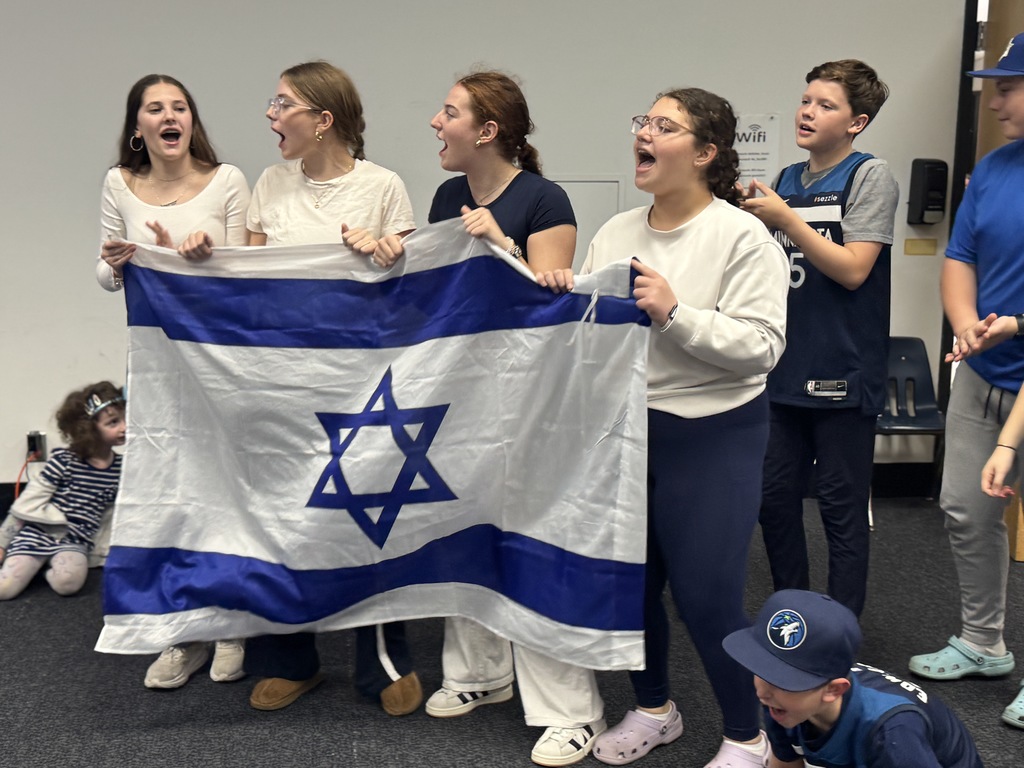 middle school girls hold Israeli flag and sing
