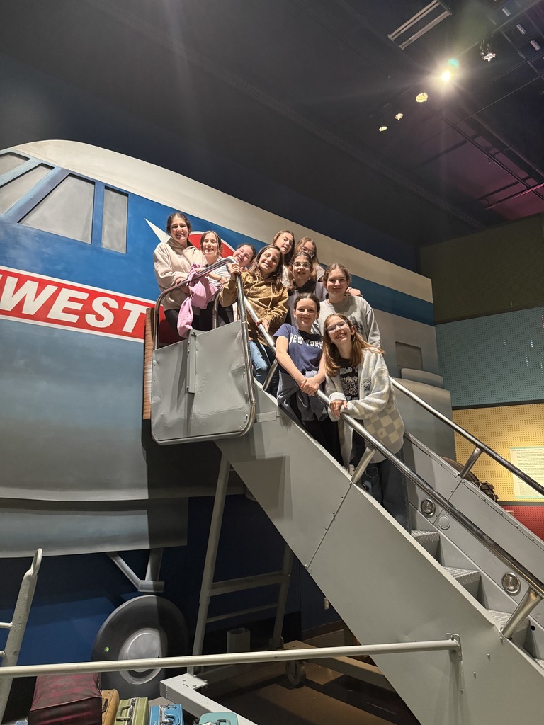 students pose on stairs up to plane in exhibit