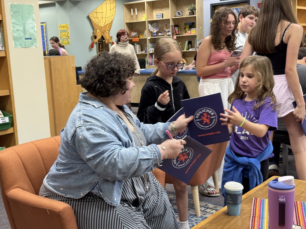 student and teacher swap yearbooks for signing
