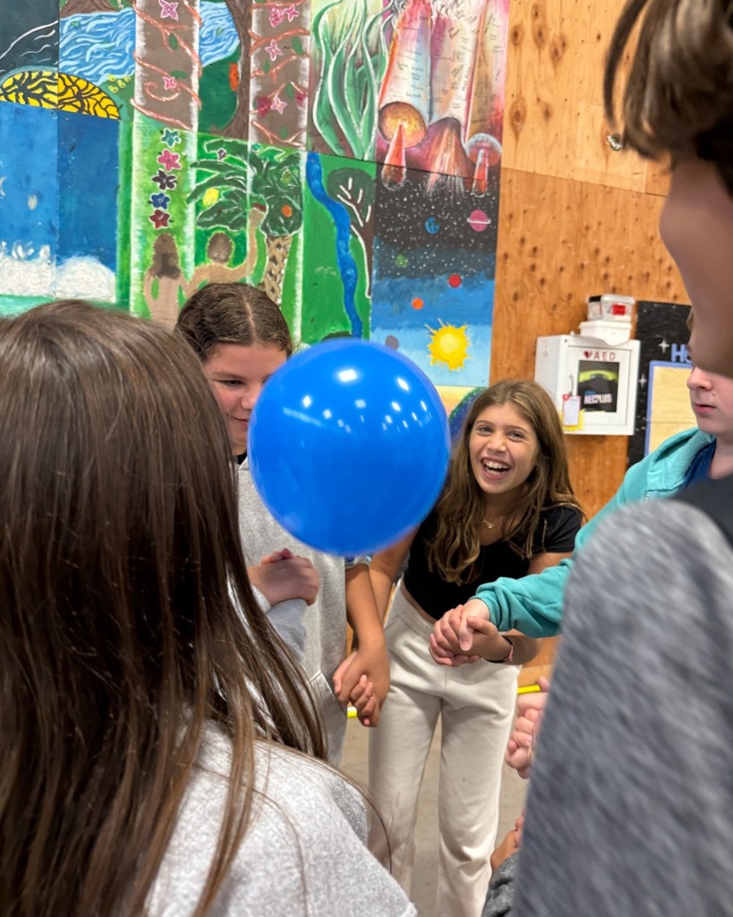 students keep balloon in the air while holding hands