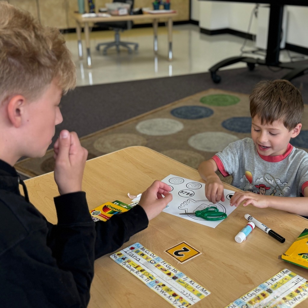 kindergartner colors Rosh Hashanah crown with eighth grade buddy