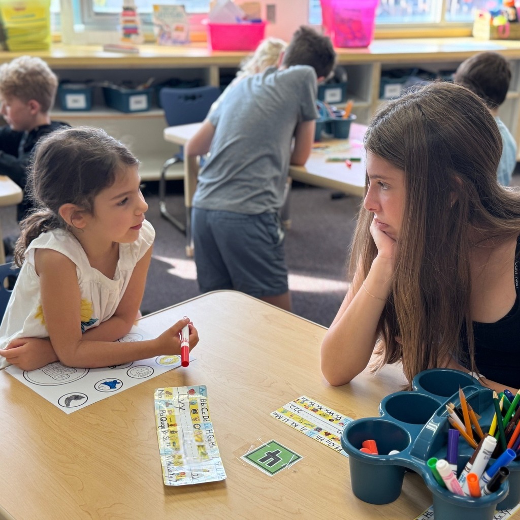 kindergartner colors Rosh Hashanah crown with eighth grade buddy
