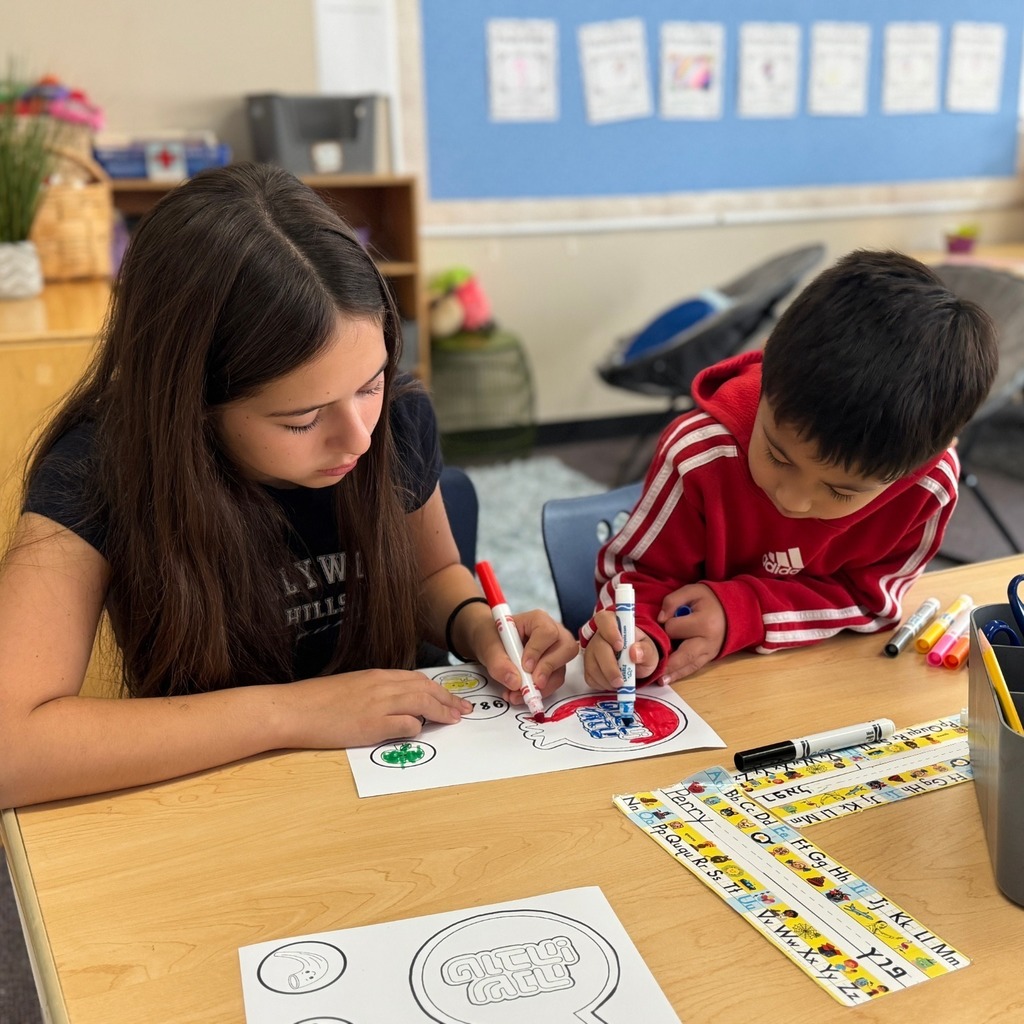 kindergartner colors Rosh Hashanah crown with eighth grade buddy