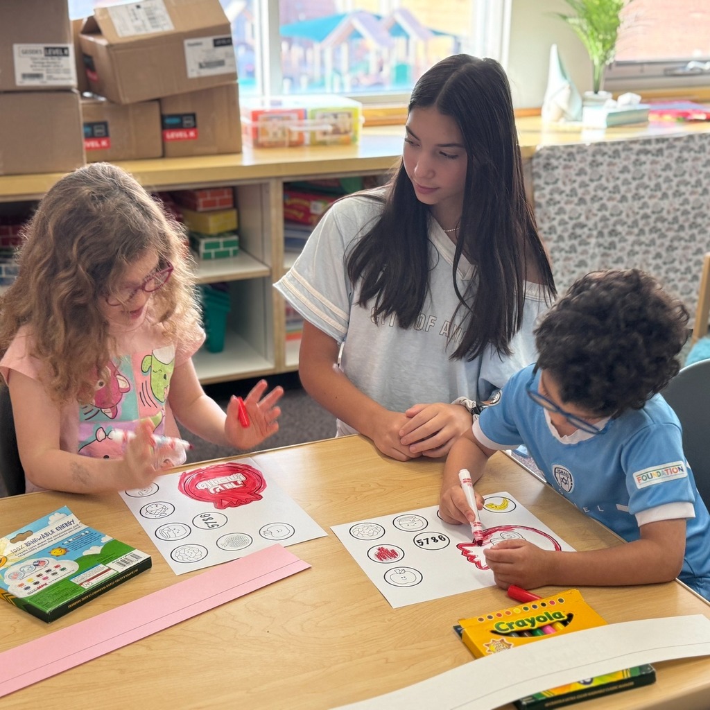 kindergartners color Rosh Hashanah crowns with eighth grade buddy