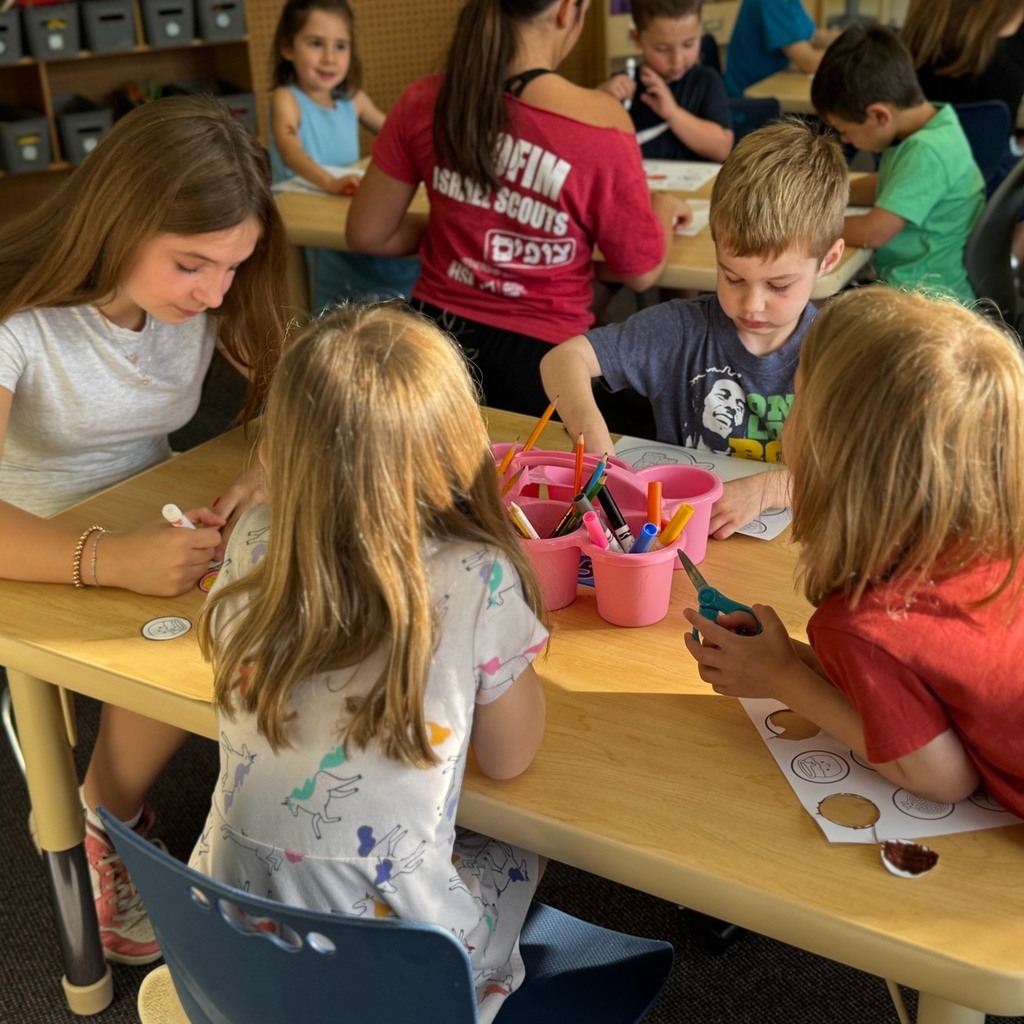 kindergartners color Rosh Hashanah crowns with eighth grade buddy