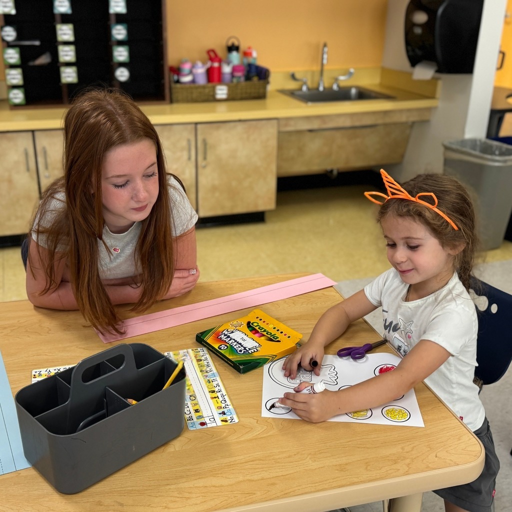 kindergartner colors Rosh Hashanah crown with eighth grade buddy