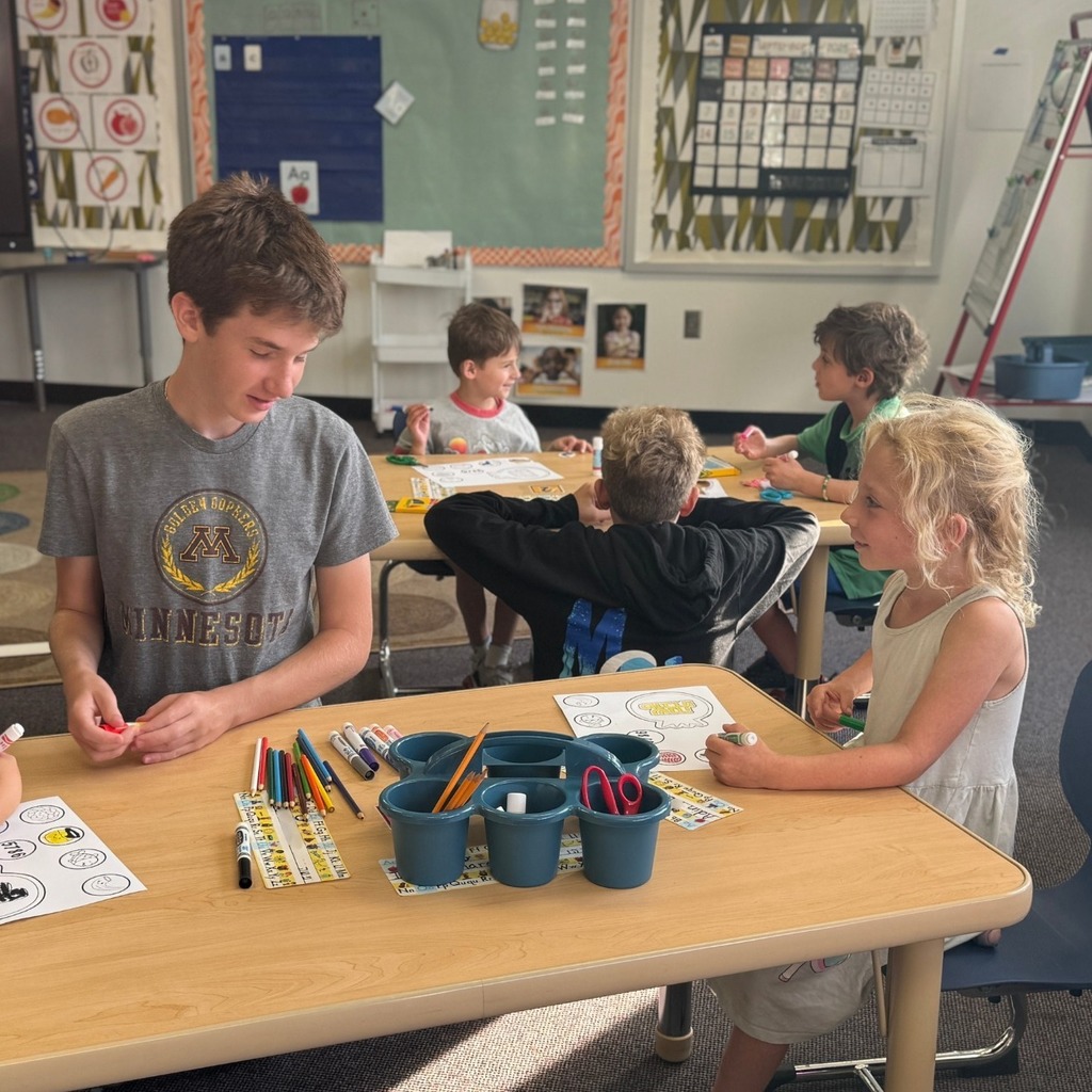kindergartner colors Rosh Hashanah crown with eighth grade buddy