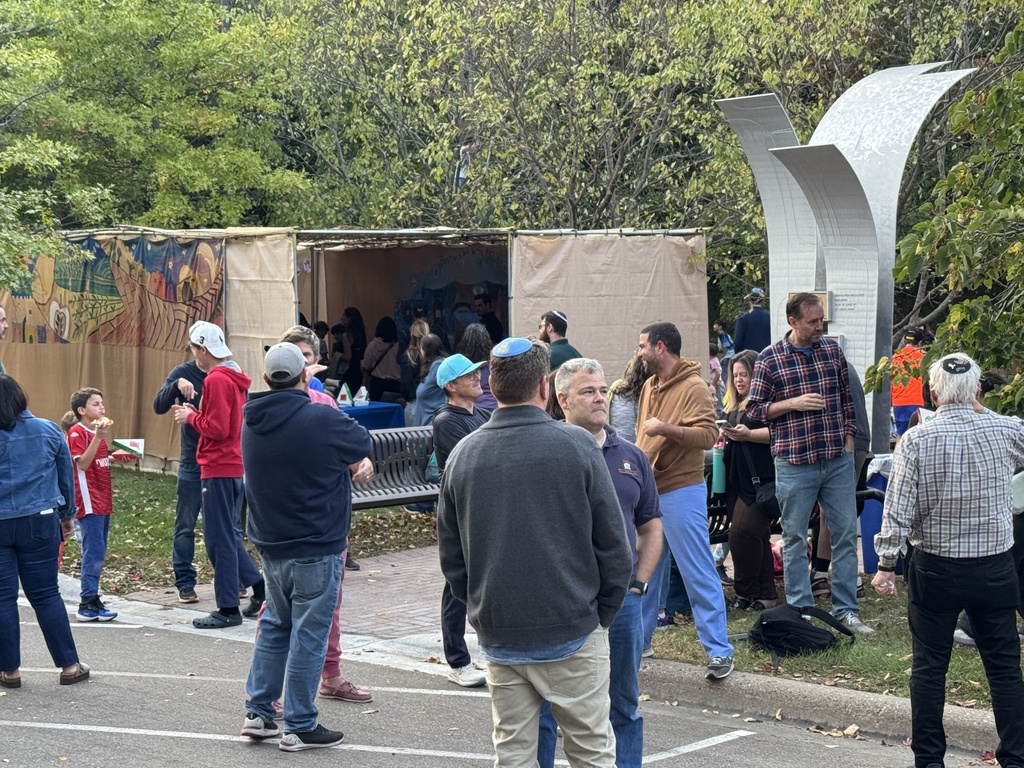 people enjoy Pizza in the Hut on lawn in and outside of sukkah