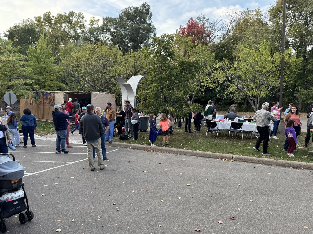 people enjoy Pizza in the Hut on lawn in and outside of sukkah