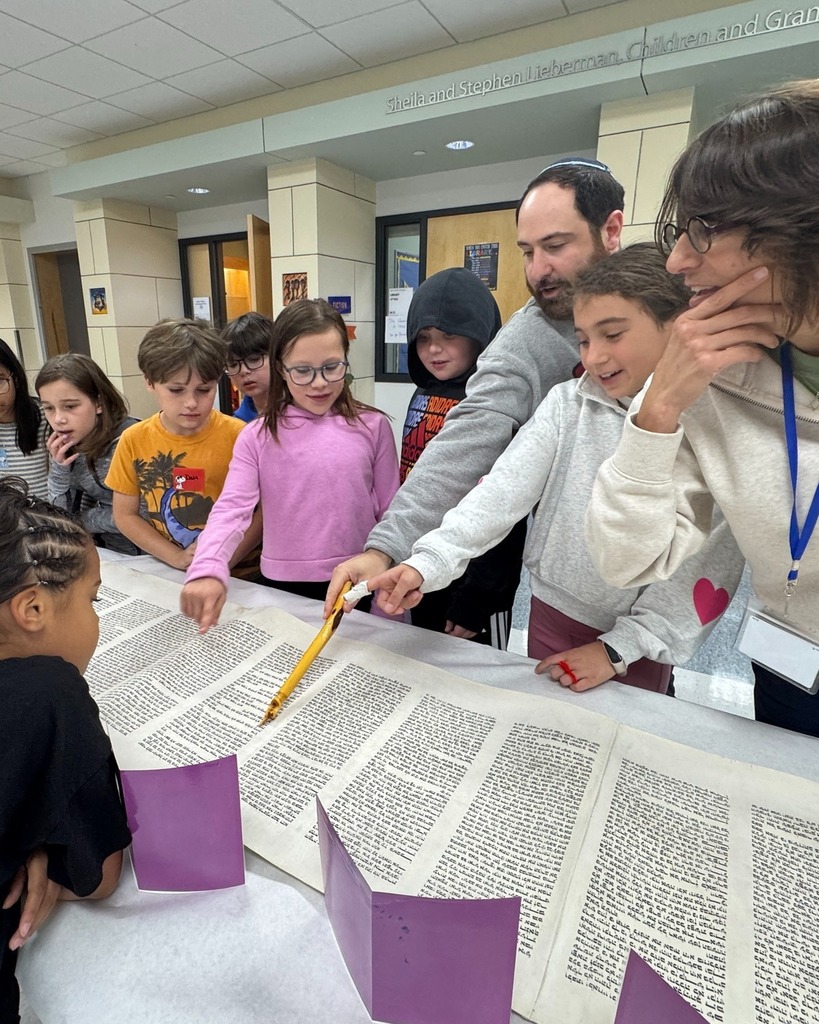 students look at Torah with Rabbi Justin