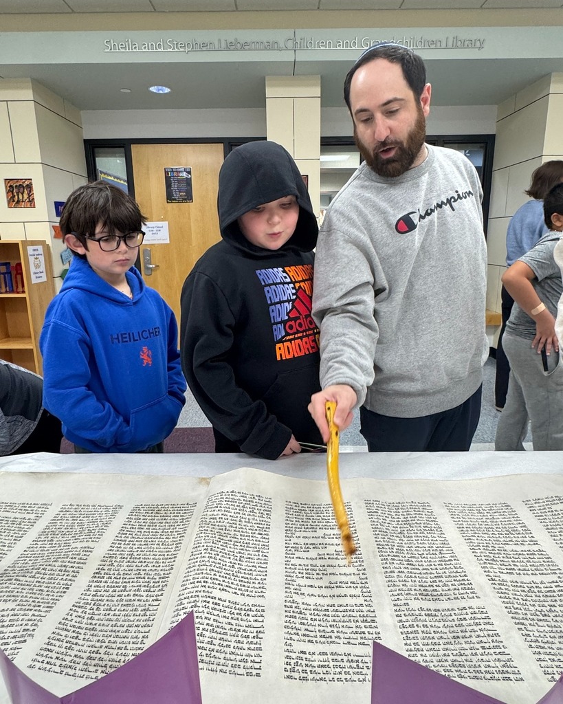 students look at Torah with Rabbi Justin