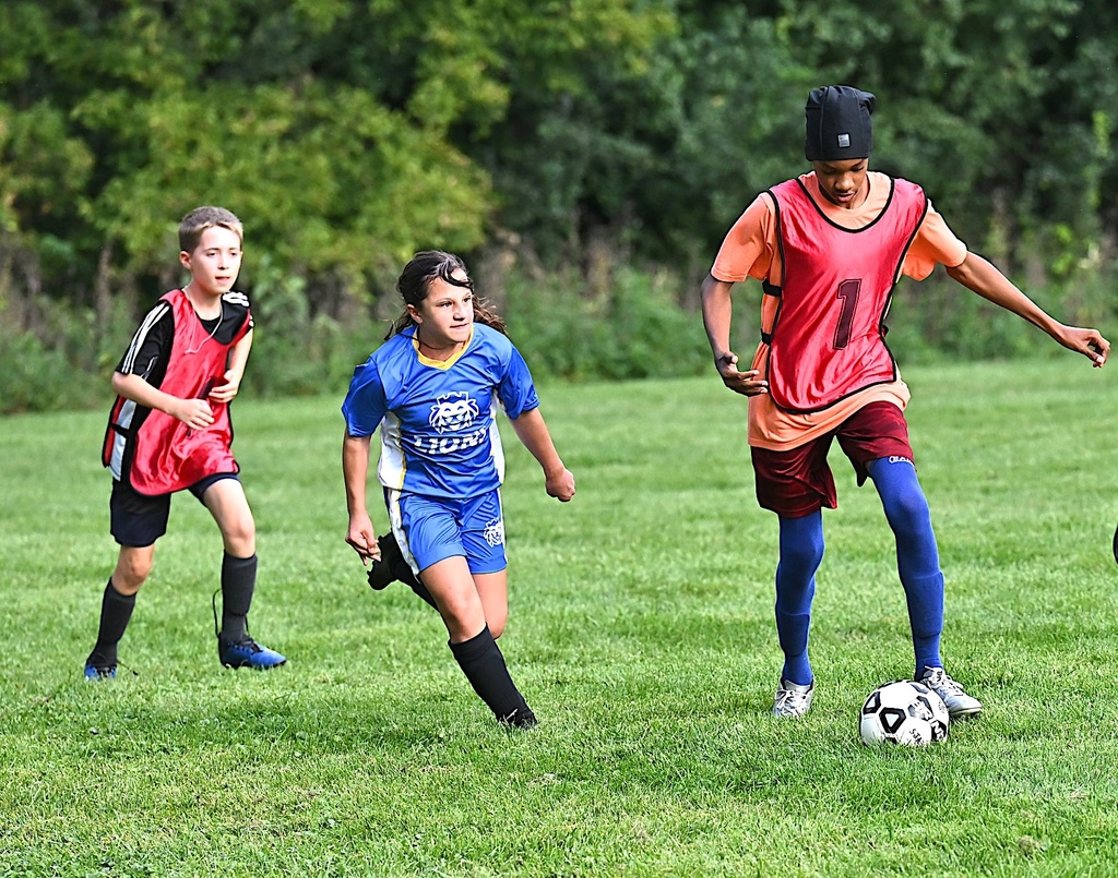 St. Helena player dribbles soccer ball with SJA player behind