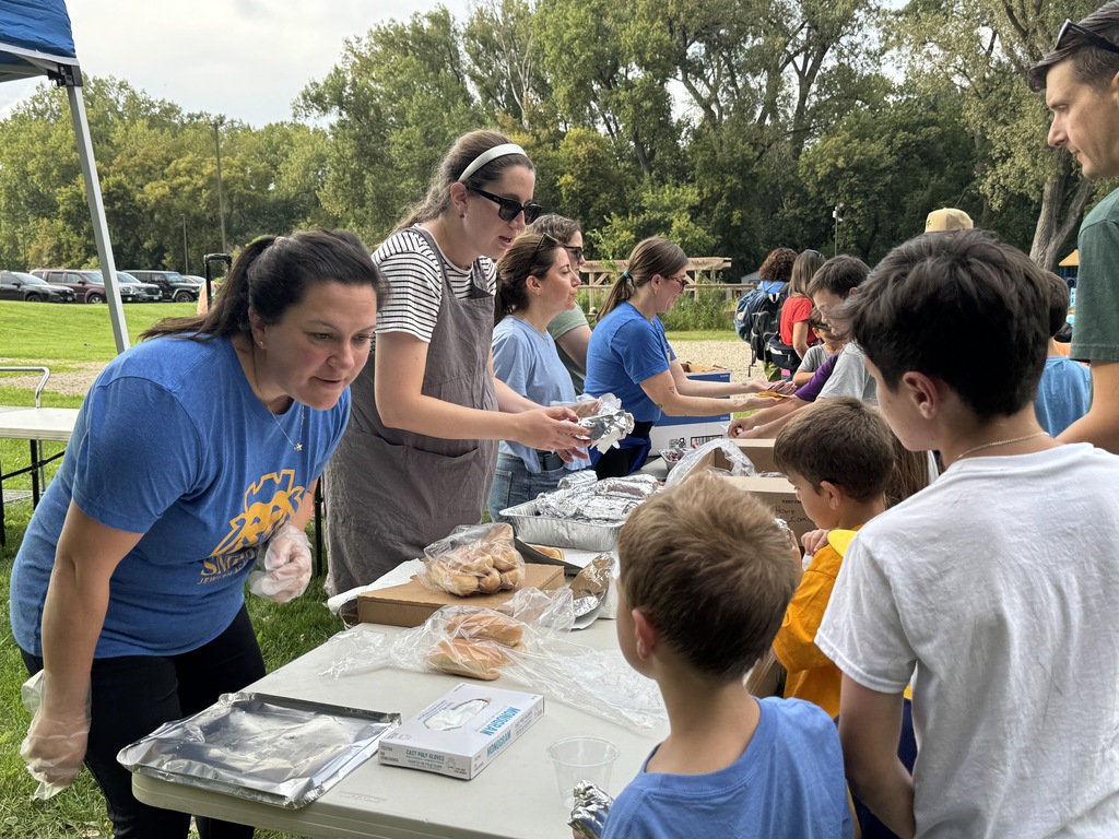 parent volunteers distribute hot dog meals to students