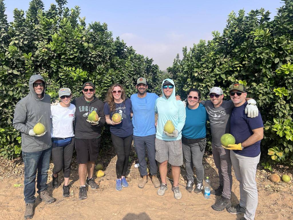 Smith parents holding pomelos in orchard of Kibbutz Holit, Israel