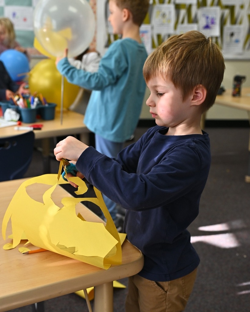 student cuts paper for parade balloon