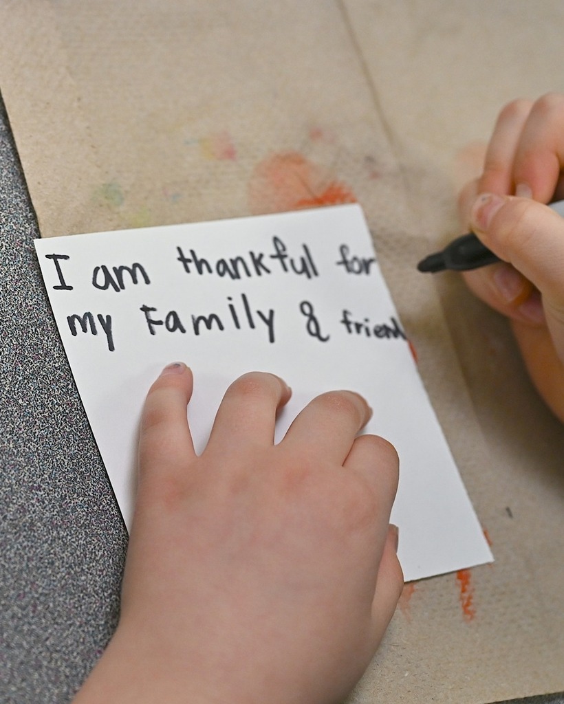 child hands write: I am thankful for my family and friends