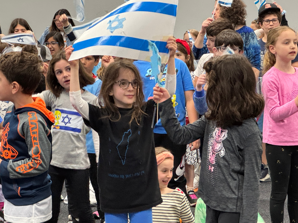students wave Israeli flags on Yom ha-Atzmaut