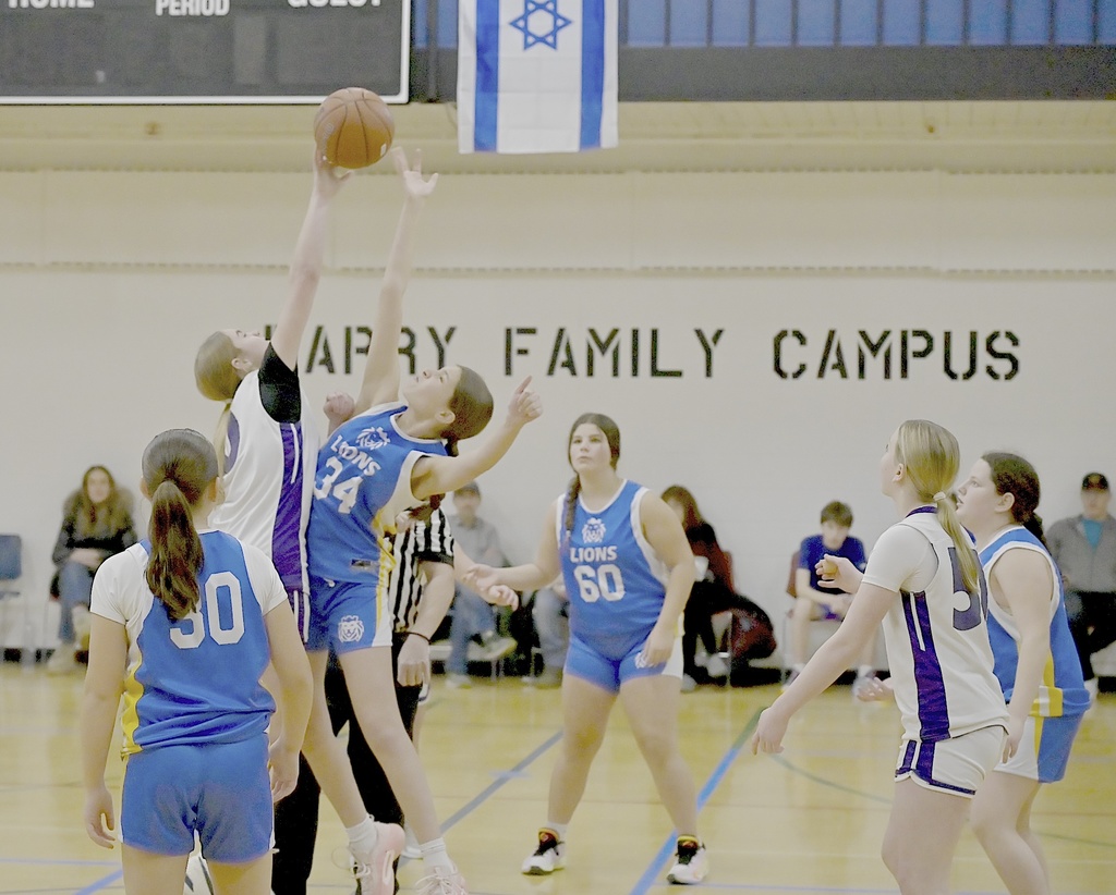 basketball players jump for ball to start game
