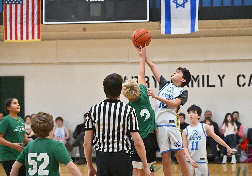 basketball players jump for ball to start game