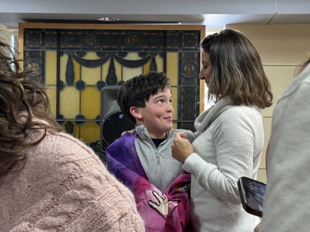 mother hugs son who is wearing his talit
