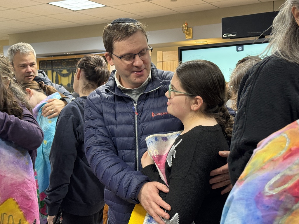 father hugs daughter who holds her wall hanging