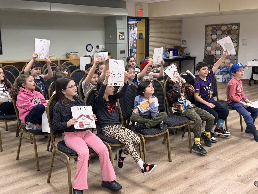 students hold up signs as they sing hashkeidiyah porachat
