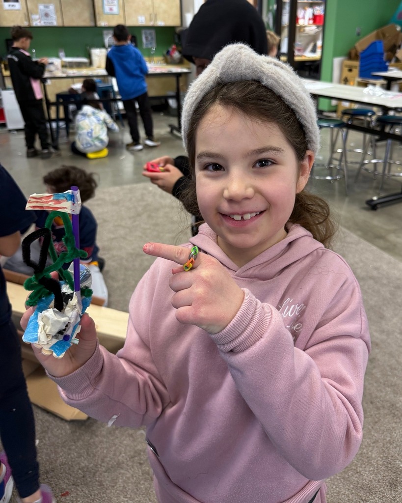 student holds homemade snowboard with pipe cleaner rider holding American flag