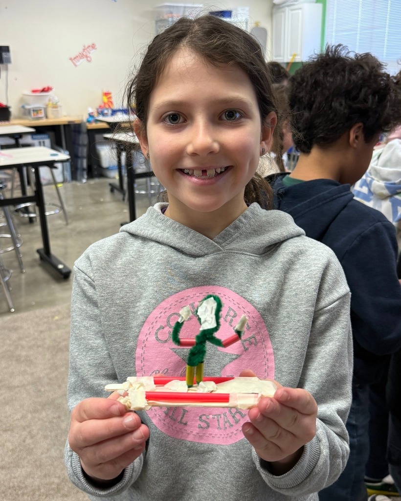 student holds homemade snowboard with pipe cleaner rider