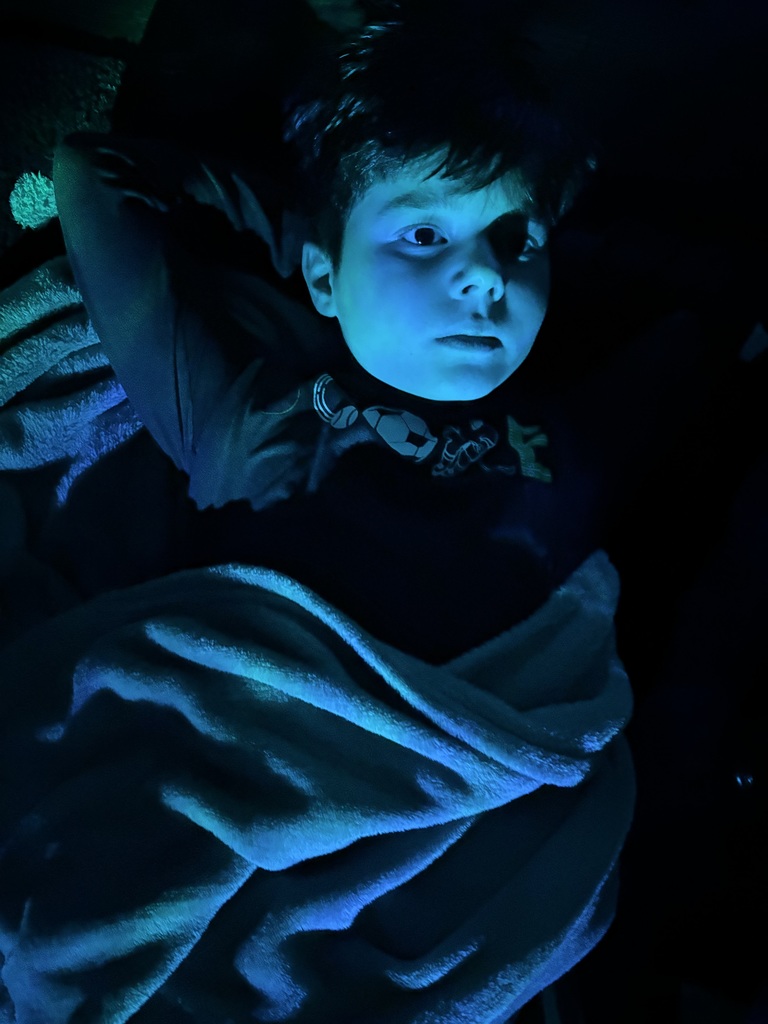 boy lies on his back in blue light