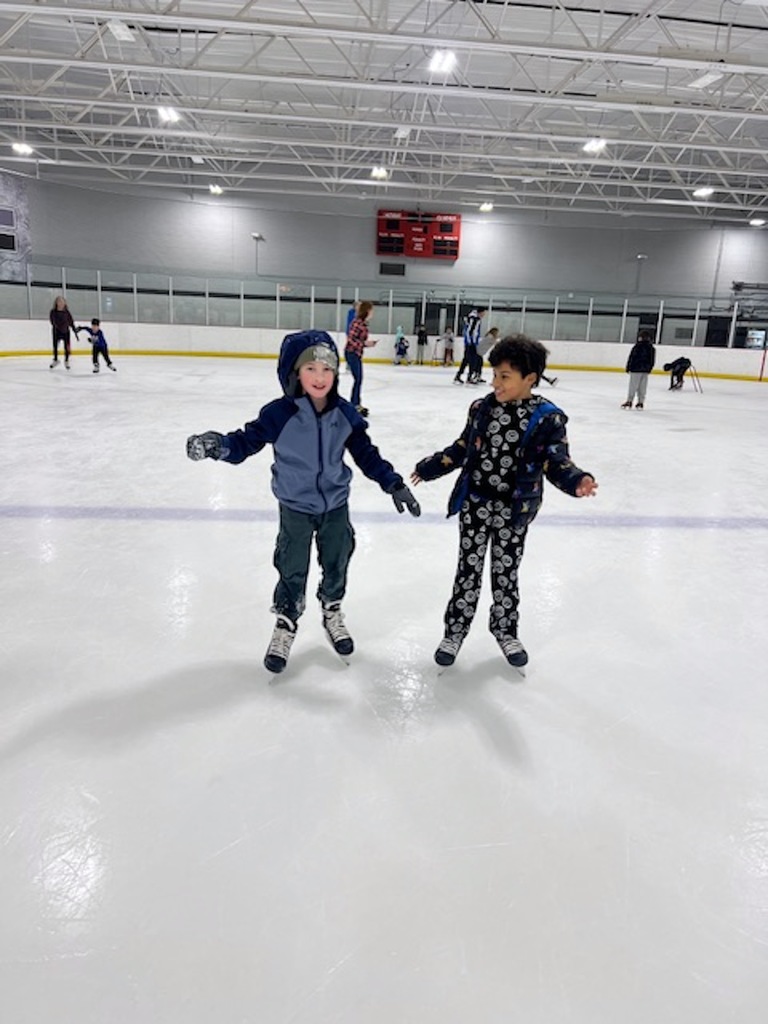 two girls skate on ice rink 