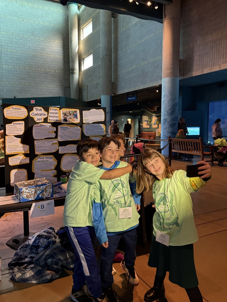 third grade team takes a selfie in front of their presentation board