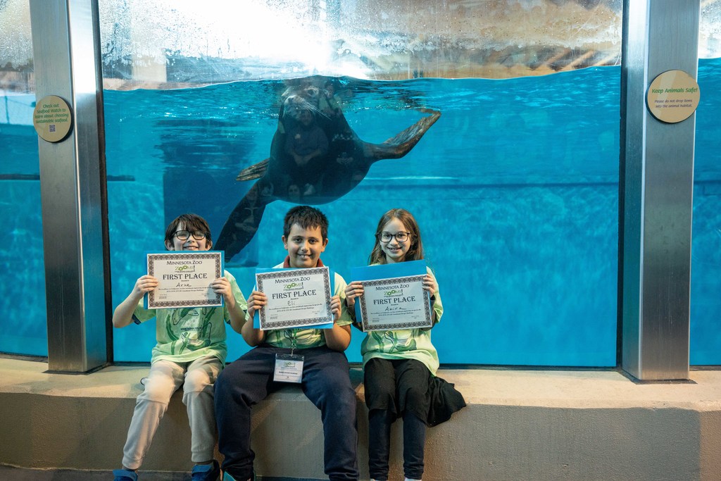 first place team poses with certificates in front of a sea lion