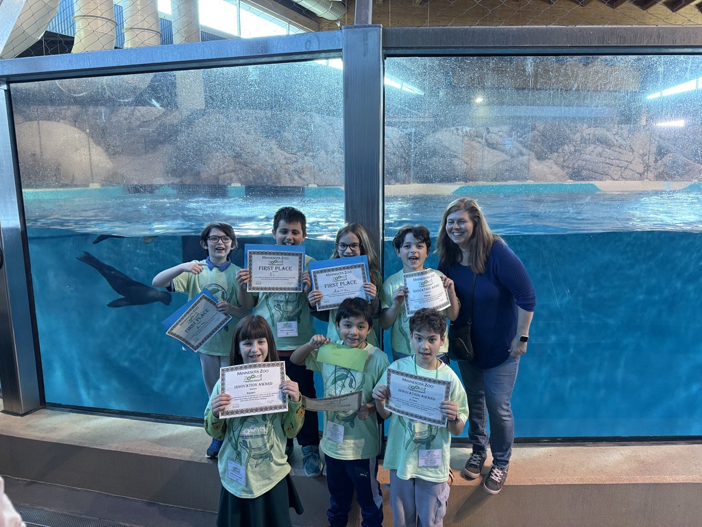 third graders pose with teacher and ZOOMS certificates in front of sea lion aquarium