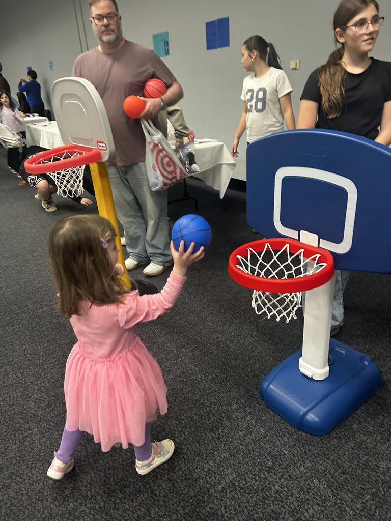 child shoots basketball into mini basketball hoop